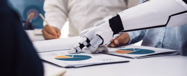 Bir robot kol, veri analizi ve modern ofis uygulamalarında teknolojinin entegrasyonunu vurgulayan bir iş toplantısında profesyonellere yardımcı olur. Noogenesis