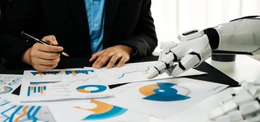 Bir iş adamı finansal verileri değerlendirirken, bir robot el de belgelere uzanarak teknoloji ve insan uzmanlığının analizlerde birleştirilmesini ön plana çıkarır.