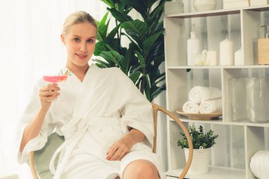 Güzellik ya da vücut bakımı güzellik salonu yaşam tarzı konsepti. Bornoz giyen bir kadın lüks otel kaplıcalarında ya da tatil odasında içkiyle rahatlıyor. Tatil ve boş zaman rahatlığı. Sessiz.