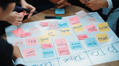 Profesyonel iş adamlarının el yazısını kapat ve çalışma kuruluna yapışkan bir not yaz. Proje yöneticisinin üst görünümü görev yaz ve zaman ve iş akışını yönetmek için kanban tahtasını kullan. Müdürlük.