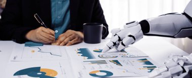 Bir insan ve robotik el, modern bir ofiste detaylı finansal çizelgeleri analiz ederek, yenilik ve teknolojiyi ön plana çıkaran bir iş toplantısına katılırlar.