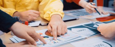 Dinamik bir ekip modern bir çalışma alanında renkli çizelgeleri inceleyerek ve iş stratejilerini tartışarak işbirlikçi bir beyin fırtınası yapıyor. SACTR