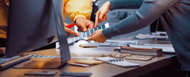 Çeşitli bireyler, yaratıcı tasarım projeleri için araçlar ve malzemelerle çevrili modern bir ofis alanında işbirlikçi bir renk seçimi sürecine girişirler. SACTR