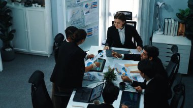 Yatırımcıların üst düzey görüşü, pazarlama fikrini toplantı masasında açıklarken, finansal belgeyi yöneticiye teslim etti. Çeşitli insanlar büyüyen grafiğe bakarken iş adamları tartışıyor. Müdürlük.