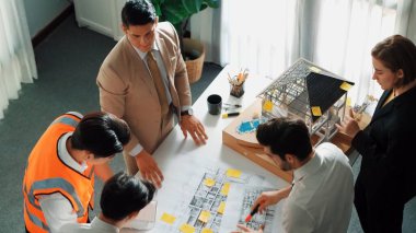 Yetenekli mimar mühendis ekibinin ev modelini incelerken proje yöneticisinin elinde bina inşaatı hakkında sorular var. Çeşitli mühendislerden oluşan bir grup birlikte çalışıyor. Hizalama.