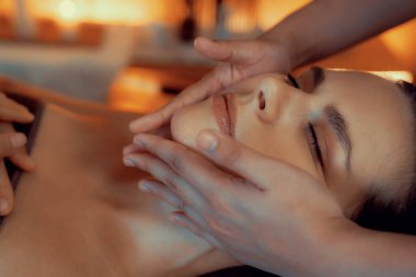 Kafkasyalı kadın stres önleyici kafa masajını yapmaktan ve lüks otel veya otelde sıcak mum ışığında yüz güzelliğini şımartmaktan zevk alıyor. Sessiz.