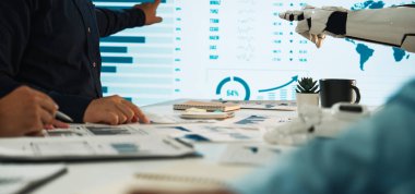 İş toplantısı sırasında iş birliği yapan insanlarla bir robotun dinamik bir sahnesi, profesyonel bir çevrede veri analizi ve teknolojik gelişimi vurguluyor. Noogenesis