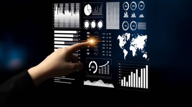 Bir kişi, modern bir ortamda çeşitli grafik ve grafikleri gösteren, iş ve teknoloji anlayışlarını ön plana çıkaran zarif bir dijital dokunmatik ekran ile etkileşim içindedir. Etki