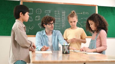 Zeki öğretmen, çeşitli çocuklar sınıf çalışması yapmak için birlikte çalışırken farklı çocukların zihin haritası çizdiği fikri açıklıyor. Çekici eğitmen öğretmek ve çalışmak hakkında konuşmak. Pedagoji.