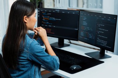 Genç Asyalı bilişim geliştiricisi güzel poz için online bilgi topluyor. Kodlama programı verileriyle birlikte kotlu tişört giyiyor. Güvenlik analizi ile çevrili iki ekran. Taktik.