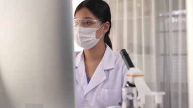 Laboratuvar kimya araştırmacısı mikroskop ve dizüstü bilgisayar kullanarak yeni ilaç ya da tedavi geliştirir. Bilimsel uzmanlığa ve laboratuvar mikrobiyoloji ekipmanlarına sahip sağlık teknolojisi. Ağır çekim. Katı.