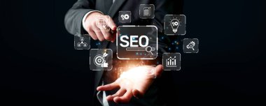 Profesyonel bir işadamı SEO kavramını sergileyerek, dijital pazarlama başarısını yönlendiren ve çevrimiçi varlığı artıran arama motoru optimizasyon stratejilerinin sembollerini vurguluyor. XDMCP