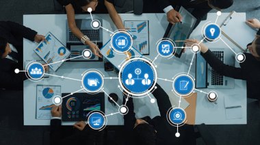 Veri analizleri üzerinde işbirliği yapan bir iş ekibinin tepeden tırnağa bir görüntüsü, ekranlarda gösterilen grafikler, modern bir çalışma alanında takım çalışmasının ve stratejik planlamanın vurgulanması. Dostluk