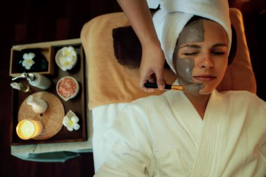 Kaplıca salonunun sakin atmosferi, üst düzey kadın müşteri sıcak mum ışığında kömür kömürü yüz kremi masajıyla kendini yenilemeye çalışıyor. Yüz bakımı ve güzellik konsepti. Sessiz.