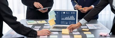 Analizci ekibi yaratıcı ve analitik beyin fırtınası fikri için bilgisayar ekranında BI veri paneli olan yapışkan bir not kullanıyor. Pazarlama stratejisi için finansal veri görselleştirme teknolojisini analiz et. Dahi.