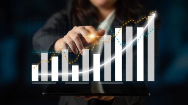 İş kadını, bir tablet kullanarak finansal büyüme gösteriyor, modern bir şirket ortamında veri eğilimleri ve içgörüleri sunuyor, başarı ve yeniliği vurguluyor. Etki
