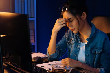 Stresli, genç, güzel Asyalı yaratıcı proje yaratıcısı sosyal medyayı araştırmak için bilgisayara bakıyor ve geceleri daha çok neon modern ofisin planlama kanalı stratejisine ulaşılıyor. Taktik.