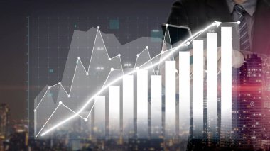 Bir işadamı modern bir ofiste duruyor, dijital grafikleri analiz ediyor ve geceleri hareketli bir kentsel ufuk çizgisine karşı finansal büyüme eğilimlerini gösteriyor. Copula