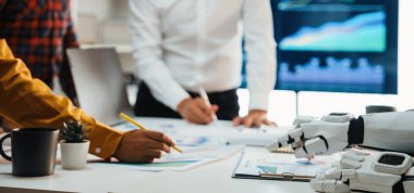 İş analizi, çizelgeler ve takım çalışmasını ve teknolojiyi yansıtan kağıtlar sergilenmesi için insan eliyle çalışan modern bir ofis sahnesi.