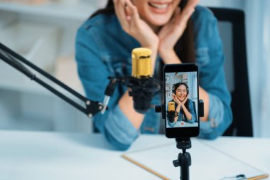 Asyalı sunucu canlı yayında canlı yayında canlı yayında sosyal medyada kulaklık takarak konuşuyor. Dinleyicileri modern stüdyoda koçluk yaparak selamlıyor. Taktik.