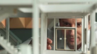 Kafkasyalı mimar mühendisinin yakın çekimi ev inşaatını denetlemek ve bina malzemelerini kontrol etmek. Proje yöneticisi modele dikkatlice bakarken kalemi işaret ediyor. Yönlendirici.