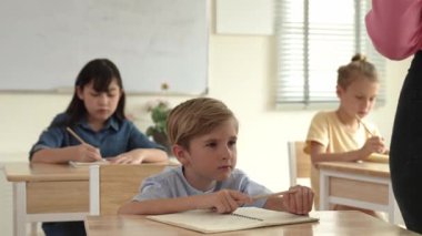 Kafkasyalı zeki çocuk, ilkokulda öğretmenlerin geçişi sırasında sınıfta okuyan çeşitli çocuklarla çevrili öğretmenlere sorduğu ve cevap verdiği için elini kaldırıyor. Eğitim konsepti. Pedagoji.