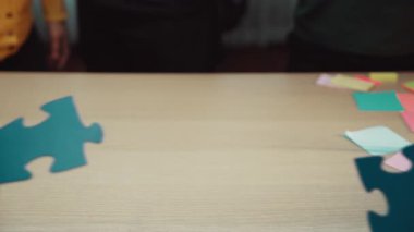 Değişik bireylerin bulmaca parçaları ve renkli notlar üzerinde işbirliği yaptığı dinamik bir iş sahnesi, takım çalışmasını ve yaratıcı beyin fırtınası çabalarını vurguluyor. SACTR