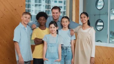 Mutlu öğretmen ve çeşitli öğrenciler kameraya gülümserken ayakta duruyorlar. Profesyonel akıllı eğitmen ve karışık ırk olan lise öğrencileri kameraya neşeli pozlar veriyor. Öğretim