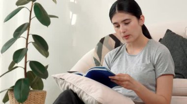 Kanepede oturan bir kadın ders kitabı okuyarak sosyal ve mesleki teknoloji bilgisini artırır ya da akıllı bir anne olmak için çocuk yetiştirir. Hayat boyu öğrenme konsepti. Uyumsuzluk.