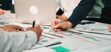 Haritalar ve belgelerle uğraşan, takım çalışması ve finansal stratejiler ve verilerin analiz edilmesinde işbirliği sergileyen kişilerin yer aldığı dinamik bir iş toplantısı. SACTR