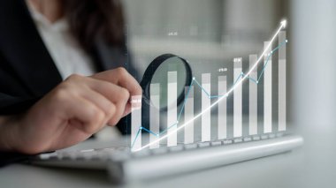 Bir iş adamı klavyede finansal verilerle ilgilenir, bir ofis ortamında büyüme grafiklerini ve eğilimlerini modern teknolojiyle analiz eder. Etki