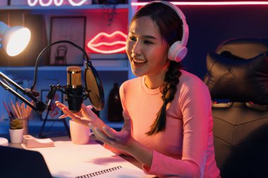 Geceleri podcast 'te olumlu konuşmalar yapan, pembe neon ışıklı modern stüdyoda sunum için dizüstü bilgisayar kullanan, gülümseyen, genç, güzel Asyalı bir etkileyiciydi. Taktik.