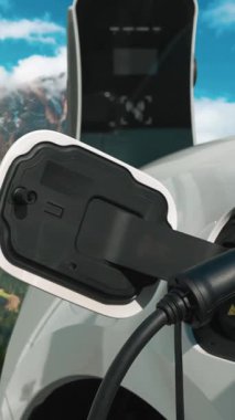 Temiz çevre için temiz enerjinin yol açtığı ilerici elektrikli araba kavramının arka planı olarak dağın tepesinde bulutun zaman kavramının yer aldığı doğal manzara. EV araba şarj istasyonunda şarj oluyor..