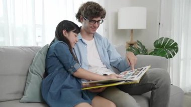 Beyaz bir baba ve tatlı bir kız kanepede otururken masal kitabı okuyorlar. Mutlu bir baba, sevimli bir Amerikan çocuğuna, birlikte zaman geçirirken hayal gücünün gelişmesi için hikaye anlatıyor. Pedagoji.