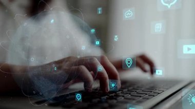 Modern bir çalışma alanı bağlamında teknoloji ve bağlantıyı temsil eden parıldayan dijital simgelerle çevrili bir klavyeye yazı yazan bir kişinin elleri. Xenic