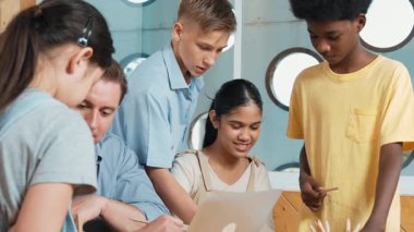 Akıllı robotlar sınıfta dizüstü bilgisayar ekranını işaret ederken, beyaz bir öğretmen yorum yapıyor ya da öğrencilere tavsiye veriyor. Öğretmen bilgisayar kullanırken çeşitli öğrencilerin ders verirken not alması. Öğretim