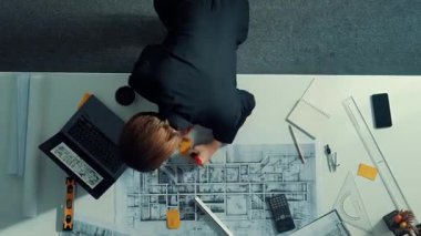 Yetenekli proje yöneticisinin proje planının zaman aşımına uğraması ve toplantı masasında bulunan mimar mühendise ekipman, cetvel, güvenlik kaskı ve dizüstü bilgisayar dağınıklığı ile ev tasarımını açıklamak. Hizalama.