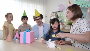 Kafkasyalı anne doğum günü pastasını kesiyor ve babaya verirken tatlıyı ayırıyor. Mutlu aile, kızının doğum gününde masada otururken parti şapkası takar. Özel durum konsepti. Pedagoji.