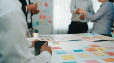 Çeşitli bir ekip, modern bir ofiste yapışkan notlar ve dijital cihazlar kullanarak, takım çalışması ve yaratıcılığı eylem halinde gösteren bir beyin fırtınası yapıyor. SACTR