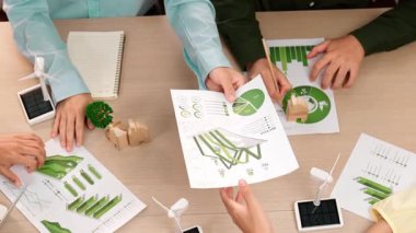 Eko evi projesini yel değirmeni tasarım modeli ve karbon ayak izini azaltmak için yeşil enerji kullanım grafiği ile toplantı masasında tartışan harika bir iş ekibi. Dünyayı kurtarın. Eline odaklan. Tanımlama.