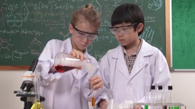 Kafkasyalı öğrenci deney yapıyor ve laboratuvarda yeni yenilikler keşfetmek için bekleyen meraklı çocuklarla çevrili biyokimyasal solüsyon döküyor. Çeşitli mutlu öğrenciler deney yapıyor. Pedagoji.