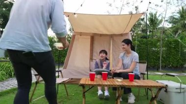 Aile hep birlikte bahçedeki kampta oturup yemek yiyor. Ebeveynler, genç nesil arasında iletişim kurmak ve zaman geçirmek için açık hava kamp faaliyetlerini kullanıyorlar. Uyumsuzluk.