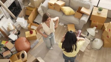 Lezbiyen çiftin dans edişinin ve oturma odasında köpük atışının yukarıdan görünüşü. Çekici oda arkadaşı müzik çalarken yeni bir eve ya da daireye taşınıyor ve kutu dağınıklığı oluyor. Myrmidon.