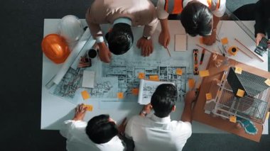 Becerikli mühendis ekibinin ev inşaatından bahsedişinin en alt görüntüsü. Mimar ya da tasarımcı grubunun planlar hakkında beyin fırtınası yapmak için tartışan ve yazan hava görüşü. Hizalama.
