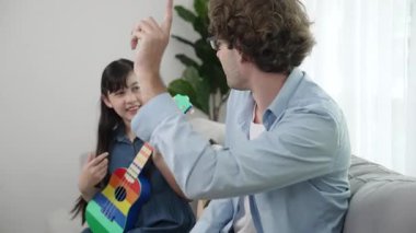 Akıllı kız oturma odasında ukulele çalarken beyaz bir babanın motivasyona ve teşviğe el çırpması. Amerikalı kız babasına gösterirken gitar öğreniyor. Aile yaratma kavramı. Pedagoji..