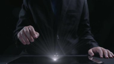 Tabletin üzerindeki eller dijital güvenliği simgeleyen, karanlık bir ortamda siber güvenlik kavramlarını temsil eden, teknolojiyi ve mahremiyeti vurgulayan bir kalkan grafiğini gösteriyor. Dörtgen