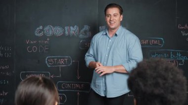 Çeşitli öğrenciler mutlulukla kollarını kaldırırken yakışıklı öğretmen başarılı bir projeyi kutlamak için el çırpıyor. Eğitmen liseli çocukları programlama eğitimine ilham vermek için alkışladı