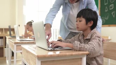 Kafkasyalı öğretmen Asyalı öğrenci kodlama mühendisliğine yardım ederken çeşitli öğrenciler yapay zeka yazılımı kullanıyor. Zeki, mutlu, çekici çocuklar, oturma ve programlama sistemi. Eğitim. Pedagoji.