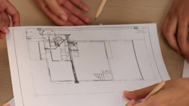 Tecrübeli mimarların her bir planı mimari projeyle karşılaştırdığı, elinde kalem tuttuğu ve iş arkadaşıyla tartıştığı bir video. İş ve çevre kavramı. Tanımlama.