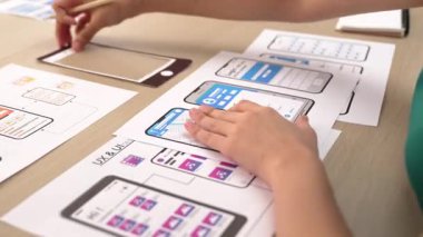 Mobil uygulama için kullanıcı arayüzü prototipi ya da masadaki program modeliyle birlikte web sitesi planlaması yapan bir şirket çalışanı. UX UI tasarımcısı kullanıcı dostu arayüz planını dikkate alır. Sinerjik